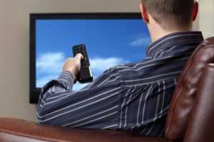 A man watching television while sitting on a sofa