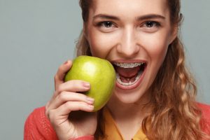Woman with braces holding fruit