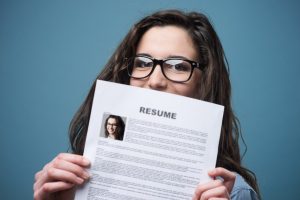 Young woman hiding behind her resume